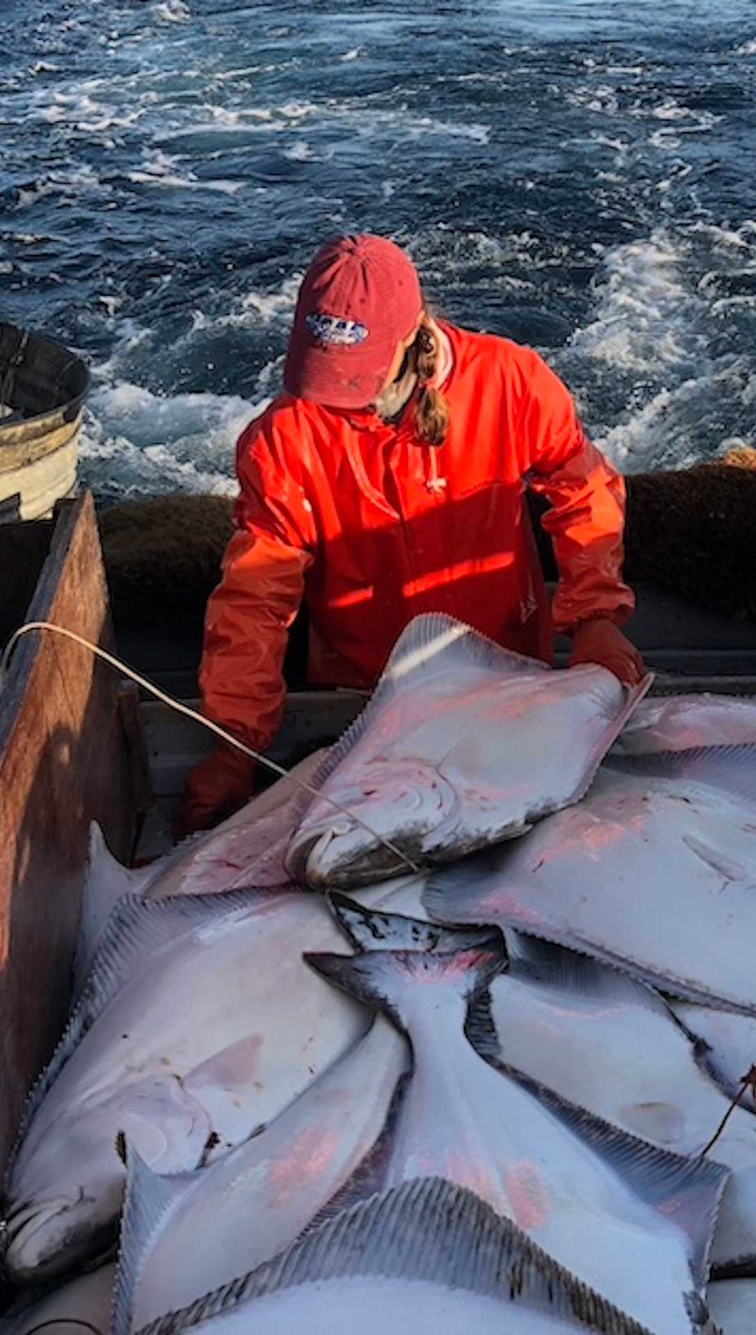 fisherman on a boat holding a halibut