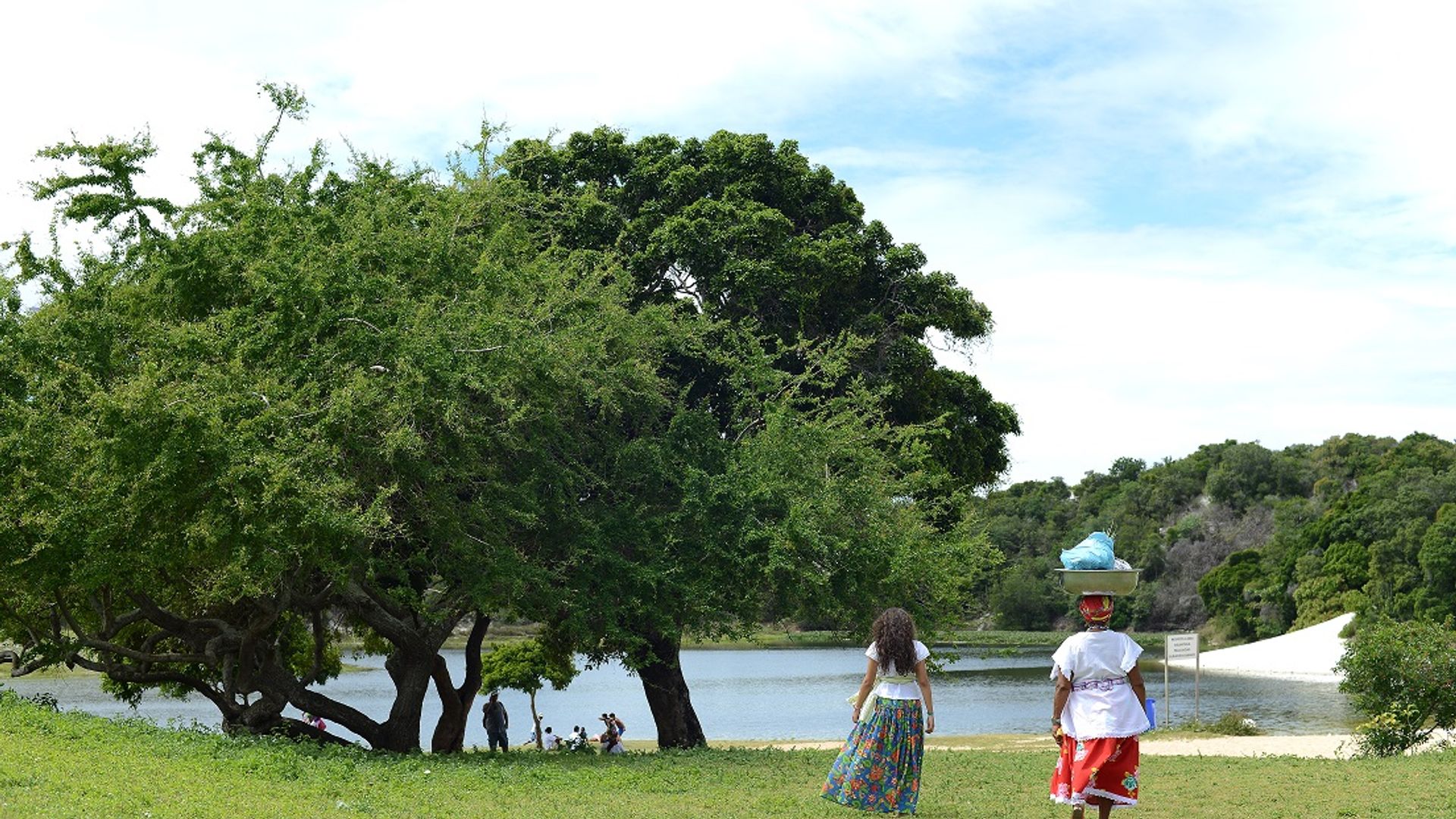 Duas ganhadeiras aparecem de costas caminhando em direção à Lagoa do Abaeté. Foto: Ricardo Prado