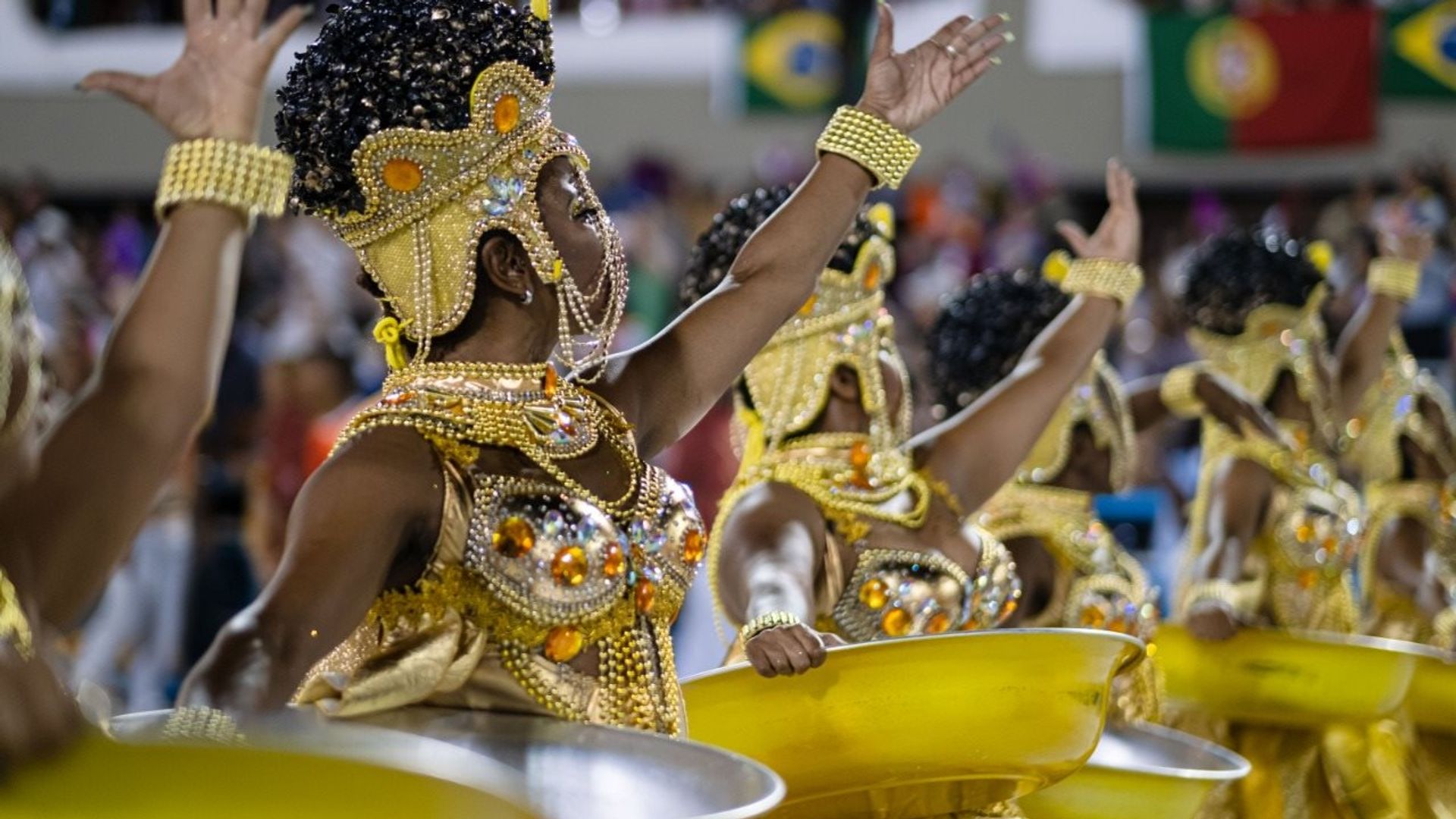 Mulheres negras vestidas de dourado seguram bacias douradas no desfile da escola Unidos da Viradouro