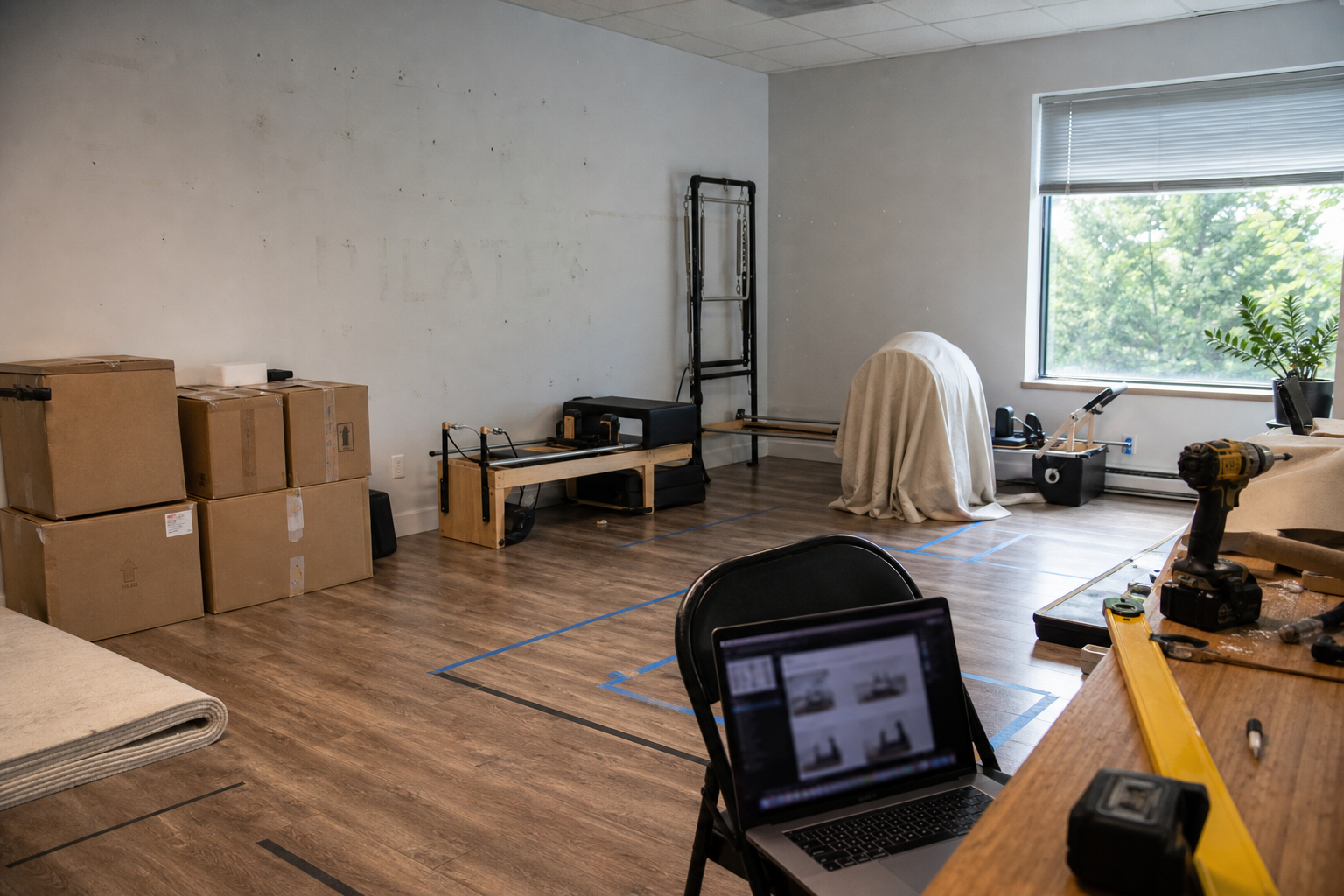 Boutique studio mid-software-migration with moving boxes, drop cloths, and a laptop showing a comparison view