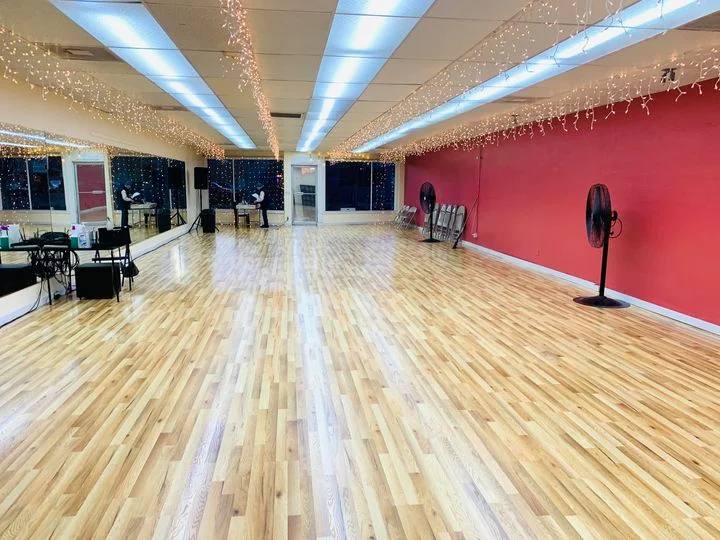Candela Dance Studio floor in Oregon, pale sprung wood, mirrored wall, red feature wall and string lights along the ceiling