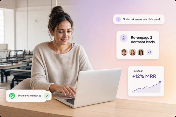Boutique studio owner reviewing the Vibe AI Business Dashboard with floating UI cards showing at-risk members, dormant lead nurture, MRR forecast, and a WhatsApp booking confirmation.