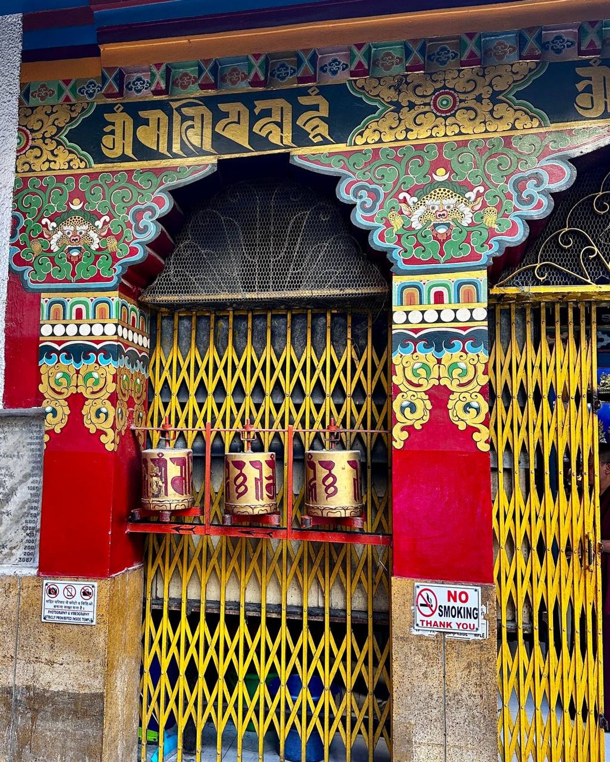 Ornate temple entrance with prayer wheels and traditional decorations
