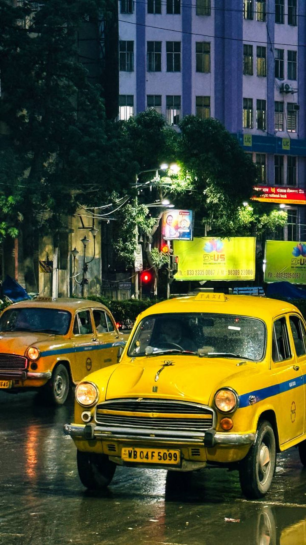 Two yellow Ambassador taxis on a rainy Kolkata night