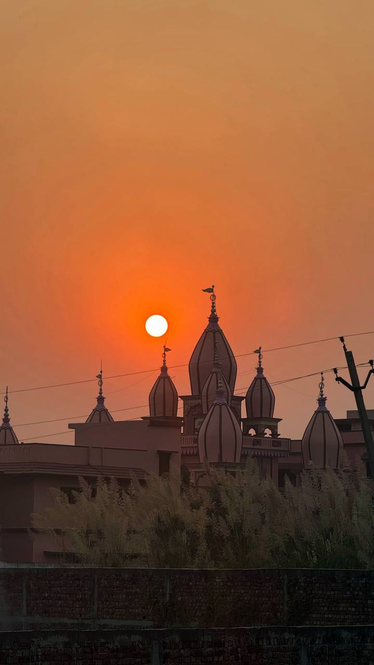 Temple spires silhouetted against an orange sunset in Vrindavan