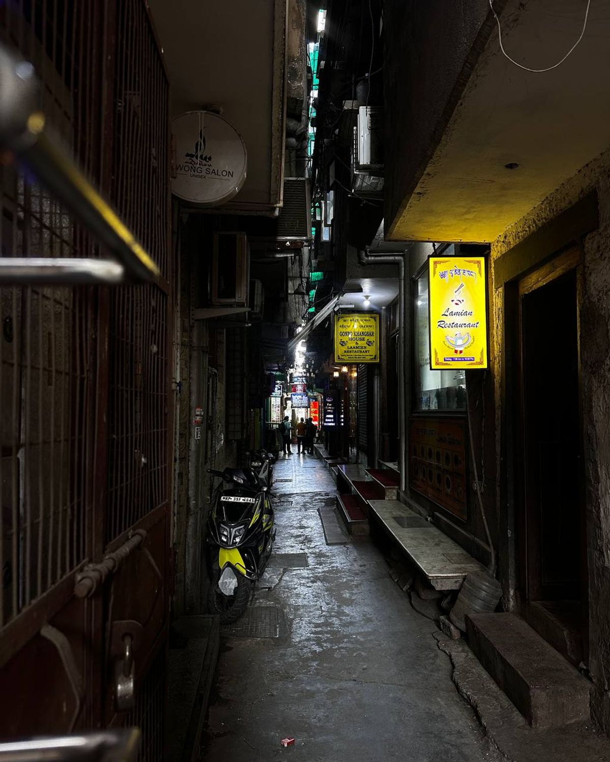 Narrow alley at night with restaurant signs glowing