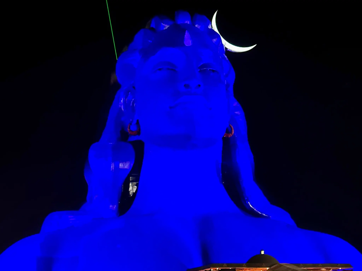 Adiyogi statue illuminated in blue light at night