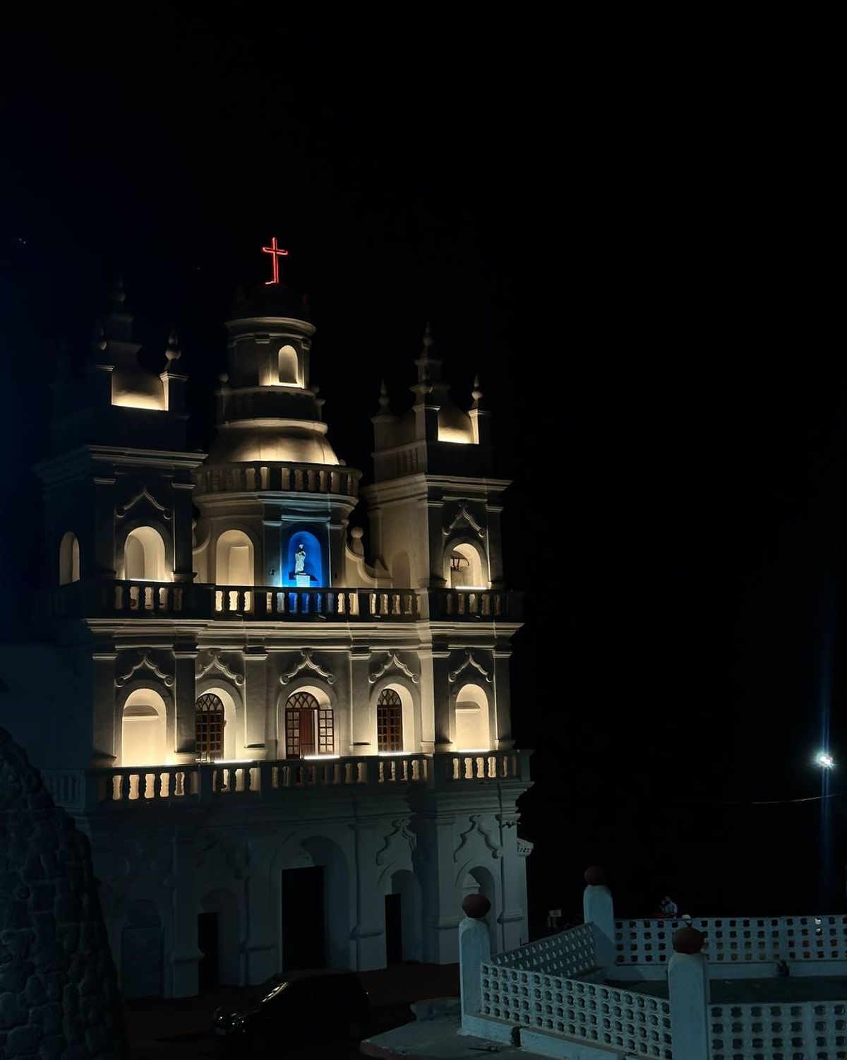 Colonial church illuminated at night with red cross