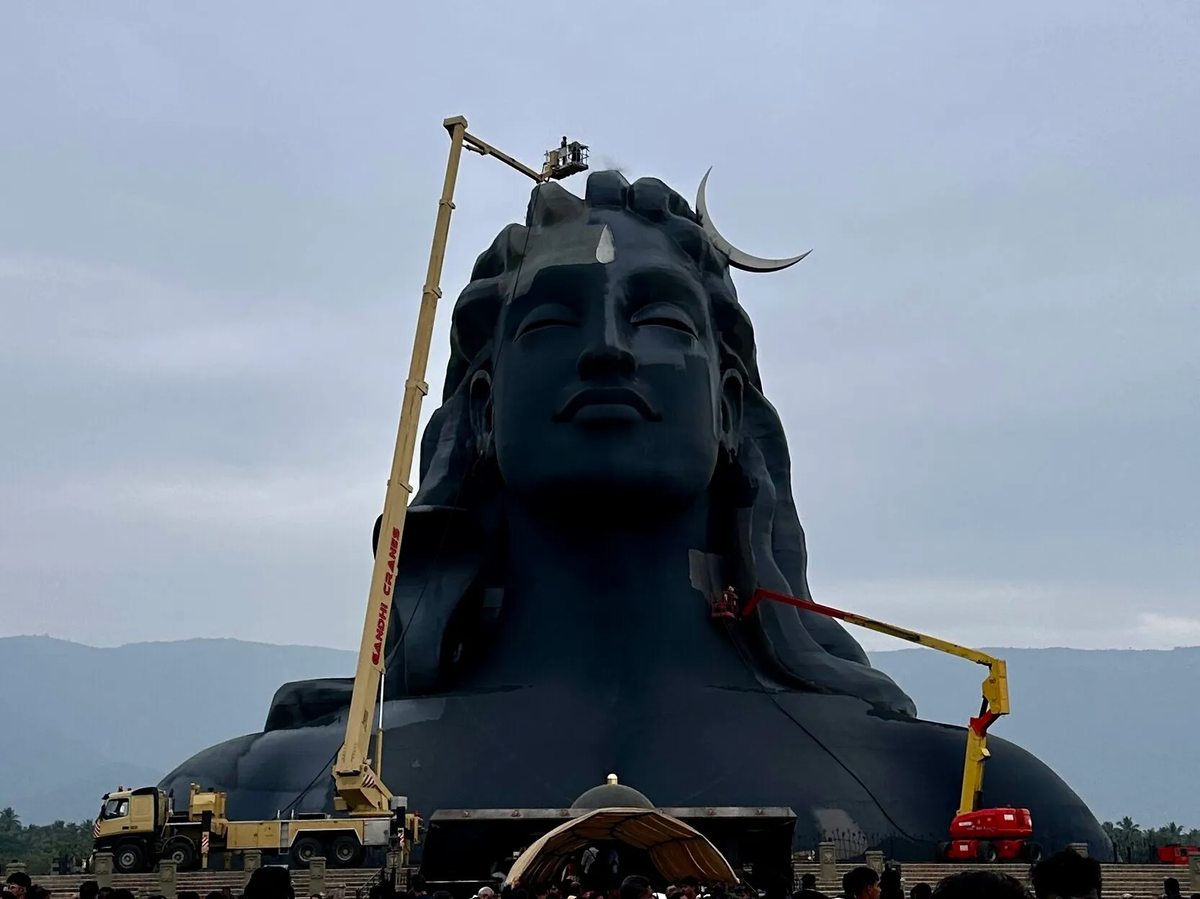 The massive 34-meter Adiyogi statue during daytime with cranes for maintenance