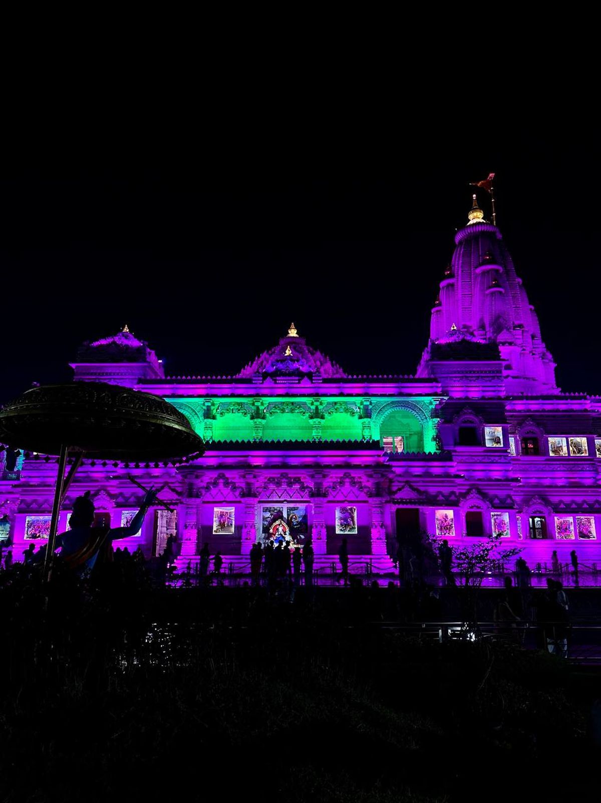 Temple illuminated at night with colorful lights
