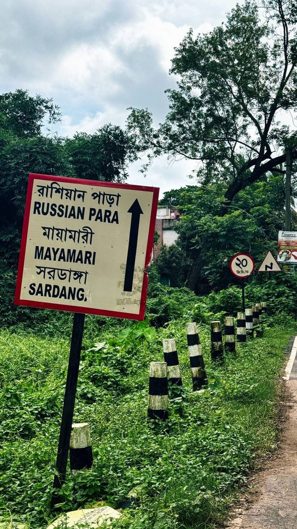 Road sign showing Russian Para in Bengali and English