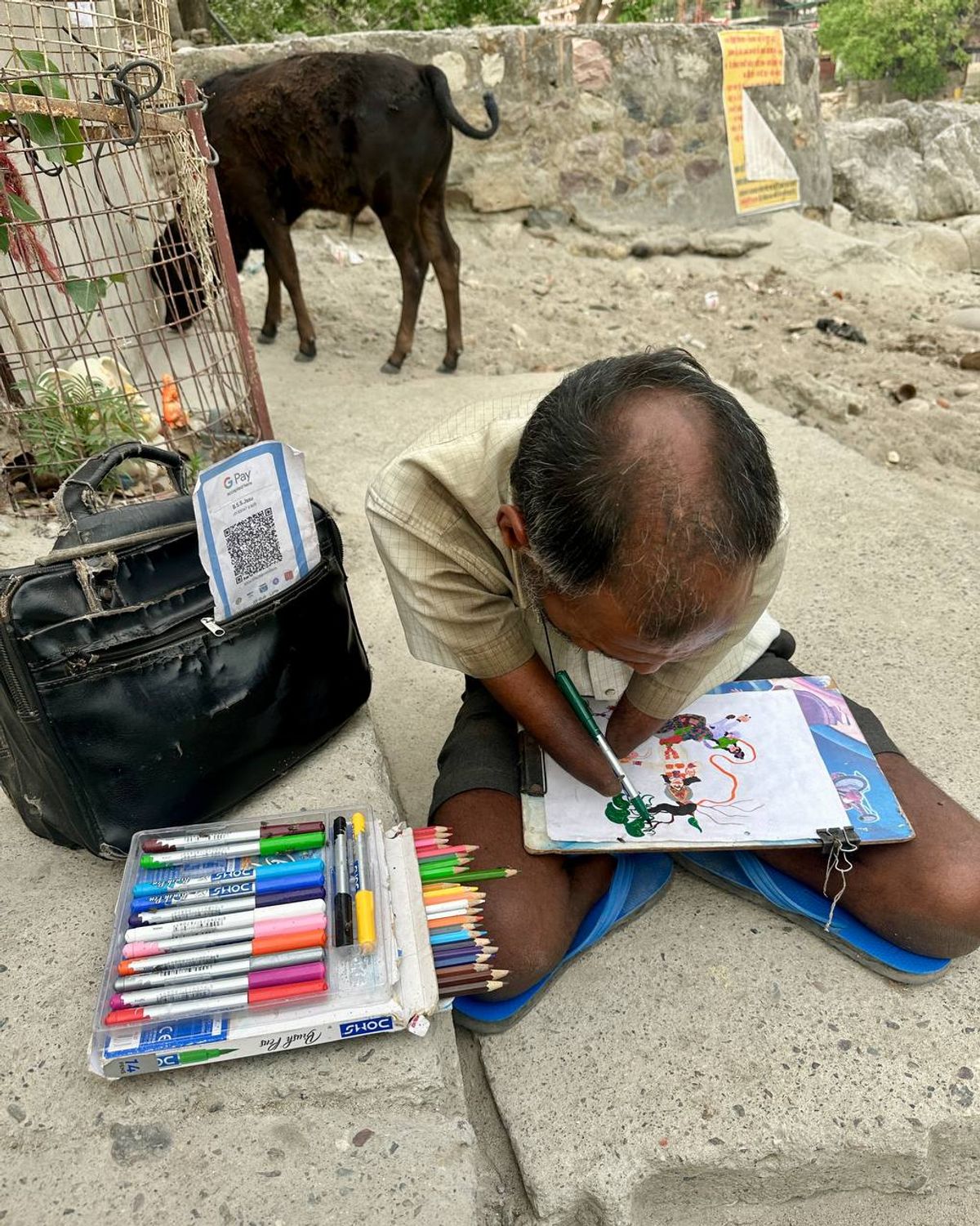 Street artist painting with his feet next to a QR code for digital payments