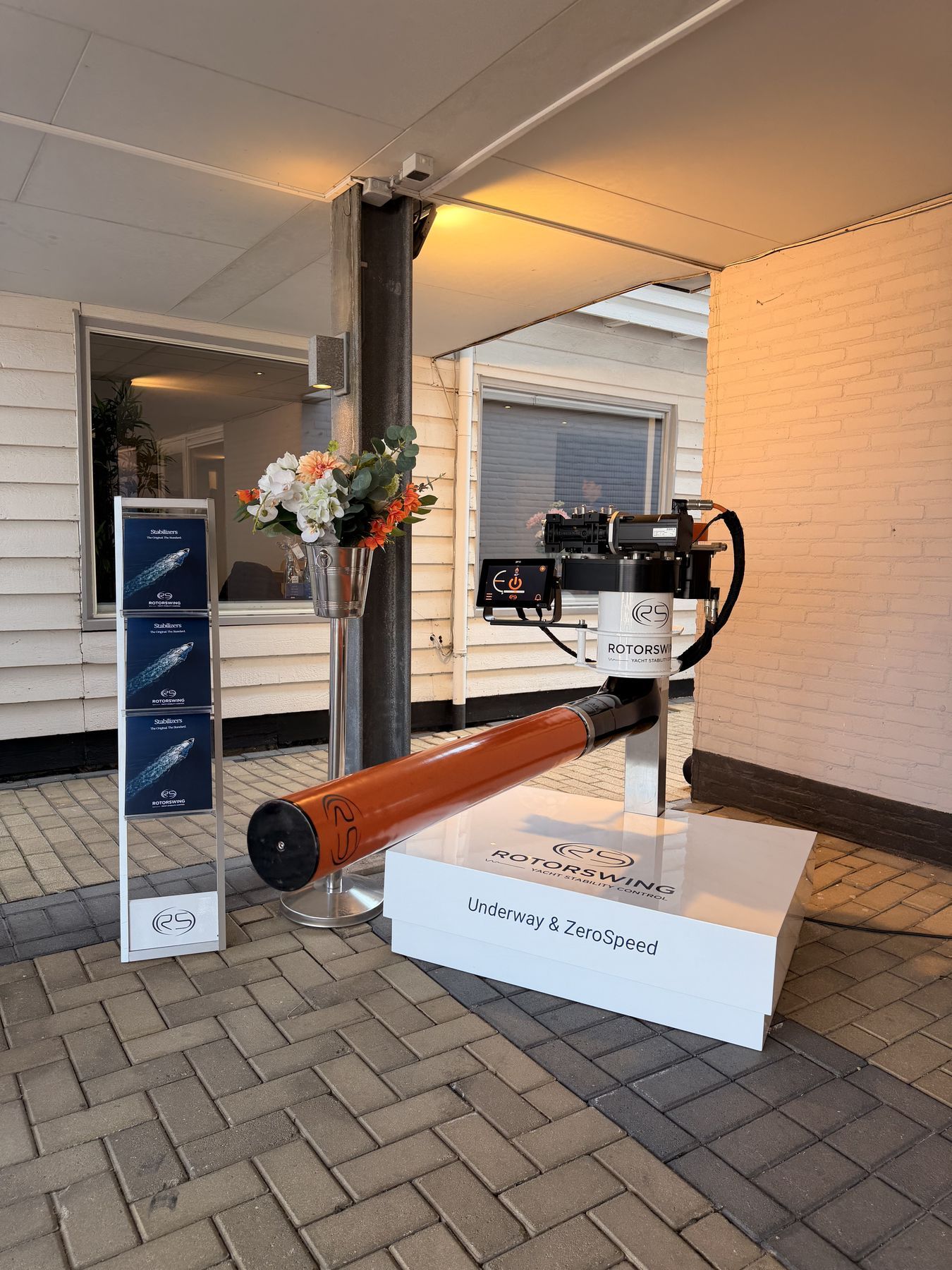 The RotorSwing display at The Yacht Experience in Loosdrecht: an orange rotor and drive head on a plinth beside the roll-up banners
