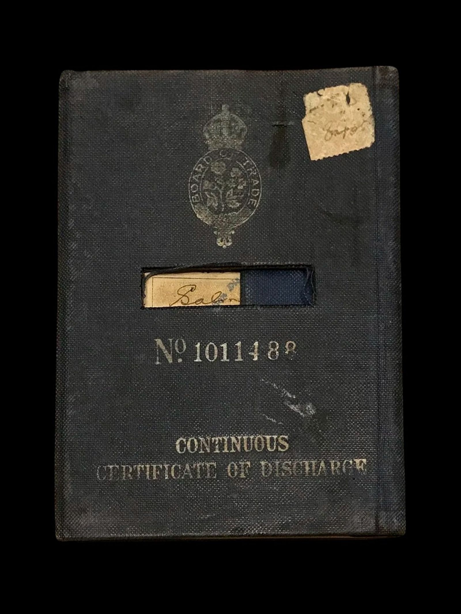 A worn dark Continuous Certificate of Discharge, a seaman's record book, with a Board of Trade crest on the cover.