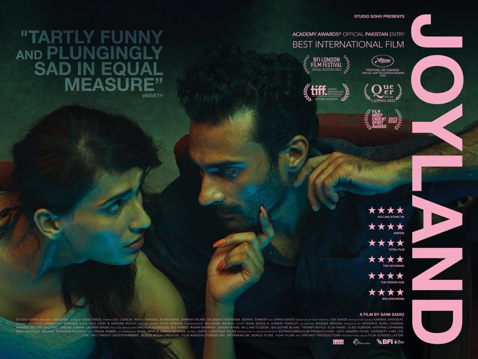 Poster for Joyland: a woman and a man lean close, looking uneasy, beside the pink title lettering and festival laurels.