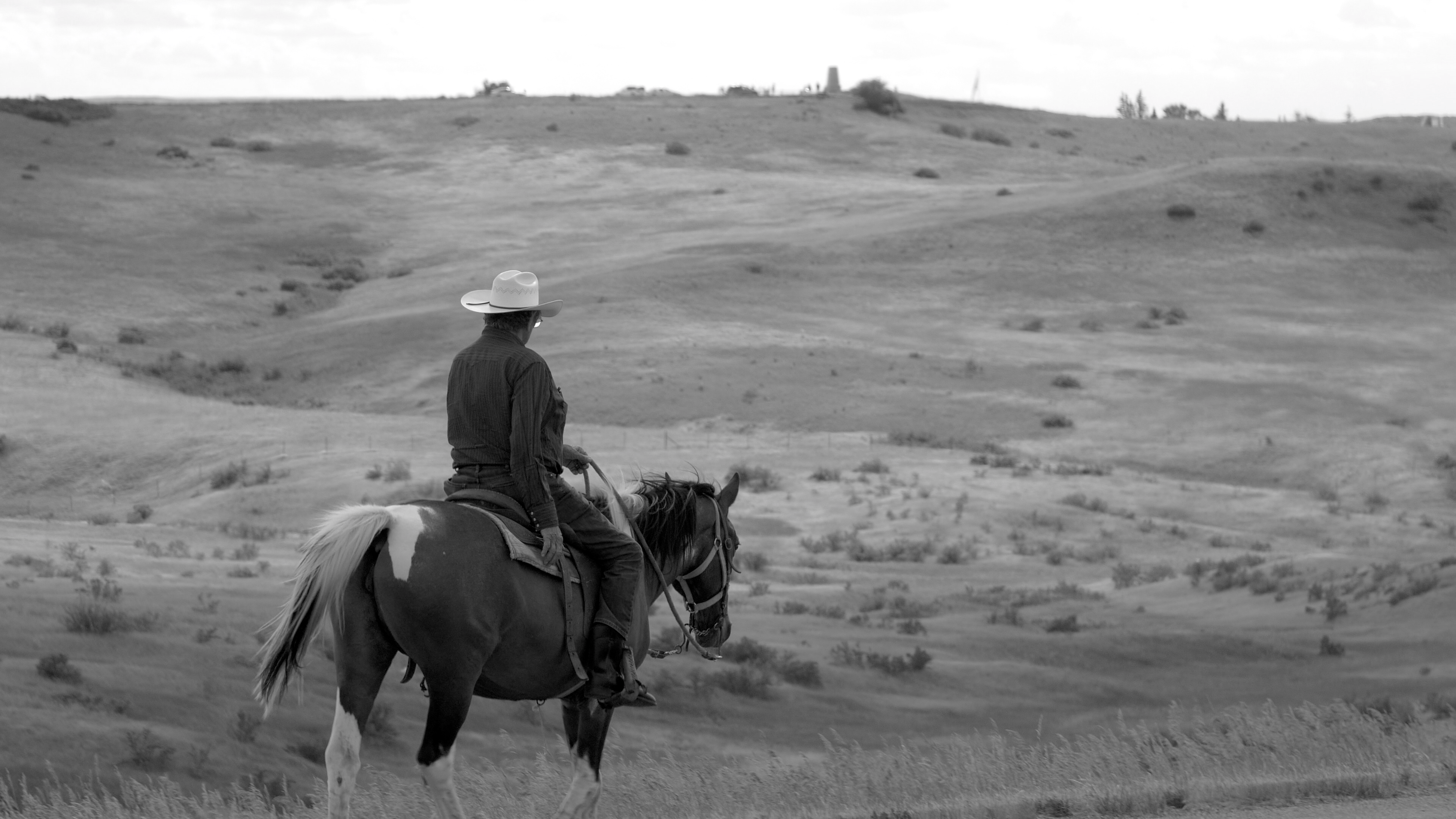 A man riding horseback across a rolling plain.