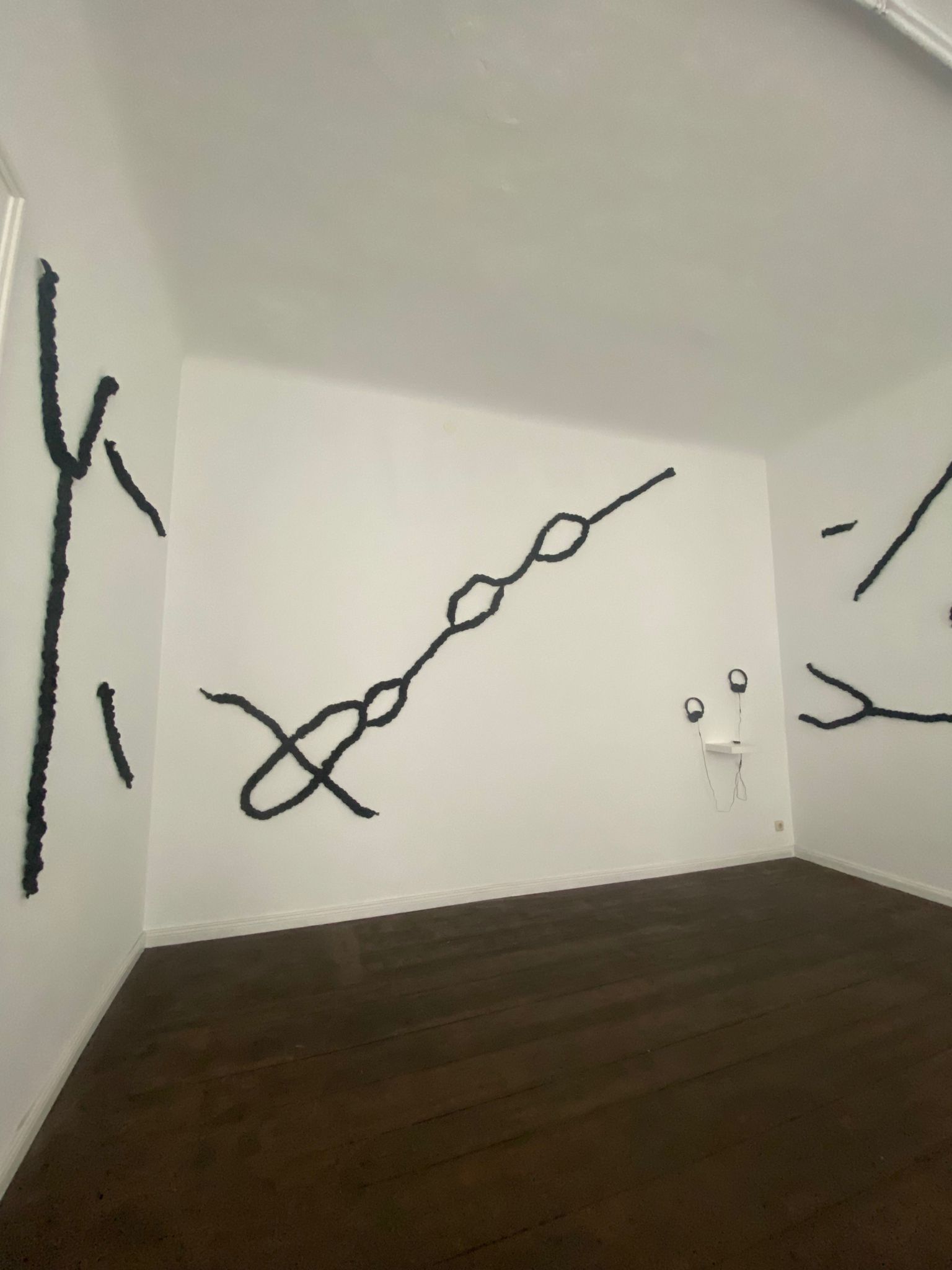 braided hair forms diagrams of streets against white gallery walls.
