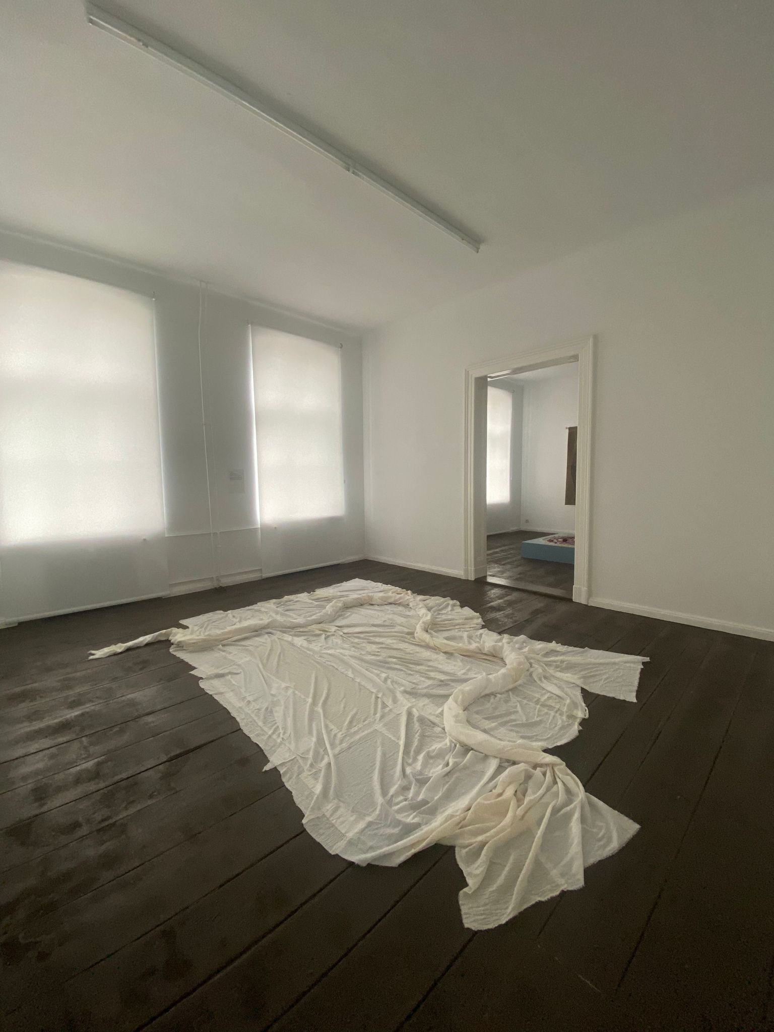 A patchwork of sheer white cloth bunches to form a serpentine organic form across the floor