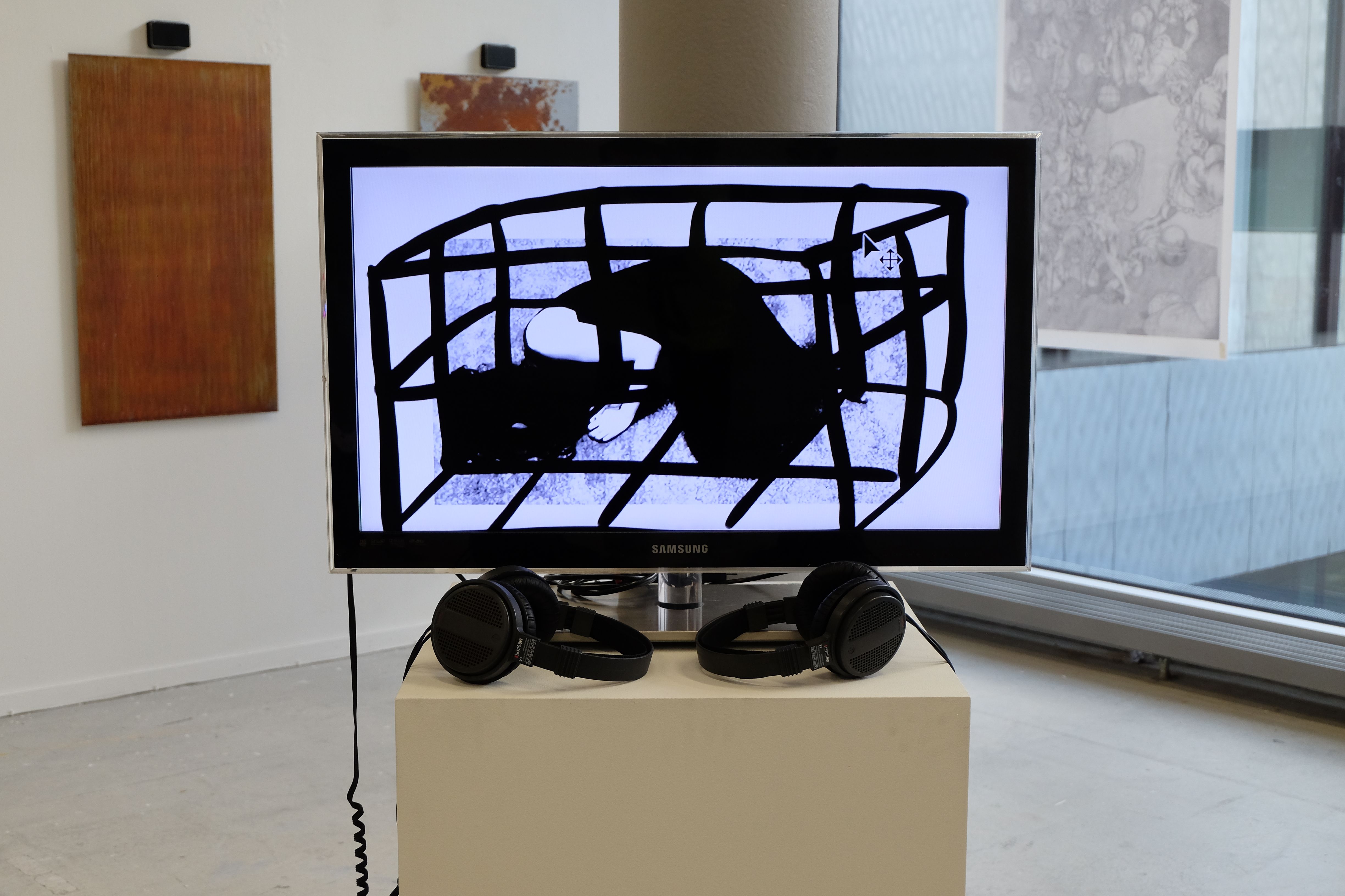 Monitor with two pairs of headphones in a gallery, showing a frame from cage-shining-pearl