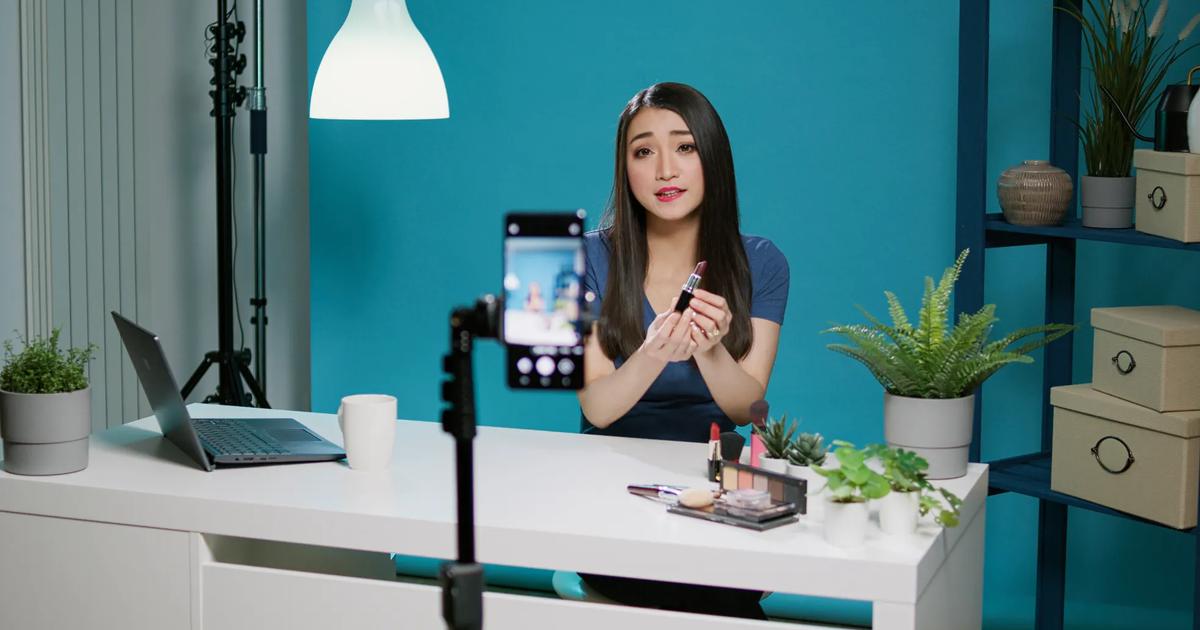 A TikTok influencer demonstrating makeup products in a home studio setup, showcasing TikTok influencer marketing strategies.