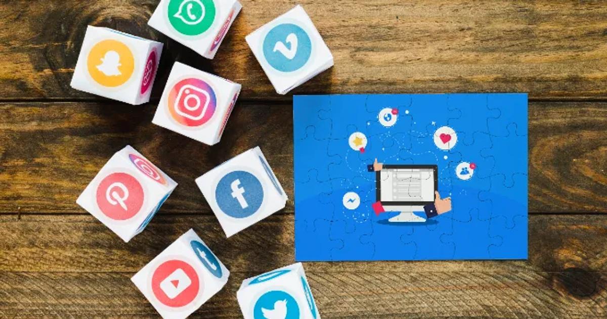Social media marketing tools concept with cubes displaying social media icons and a digital marketing illustration on a wooden surface.