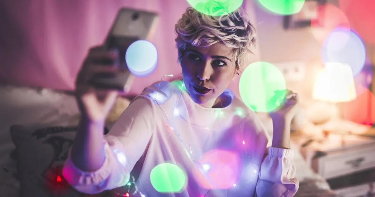 Young influencer taking a selfie surrounded by colorful lights, representing creativity in an AI-powered influencer marketing campaign.