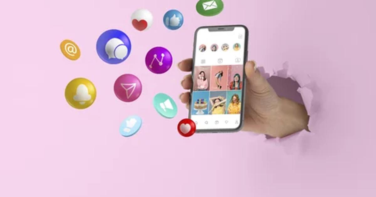 A hand holding a smartphone displaying a social media interface, surrounded by colorful social media icons, symbolizing social media marketing trends.