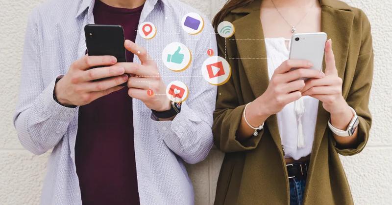 Two people using smartphones with social media icons, illustrating the concept of social media marketing.