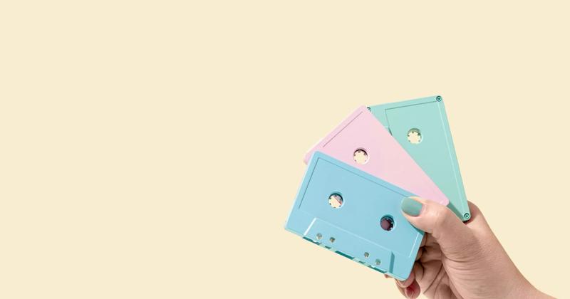 A hand holding pastel-colored cassette tapes, symbolizing creativity and nostalgia in social media marketing strategies.