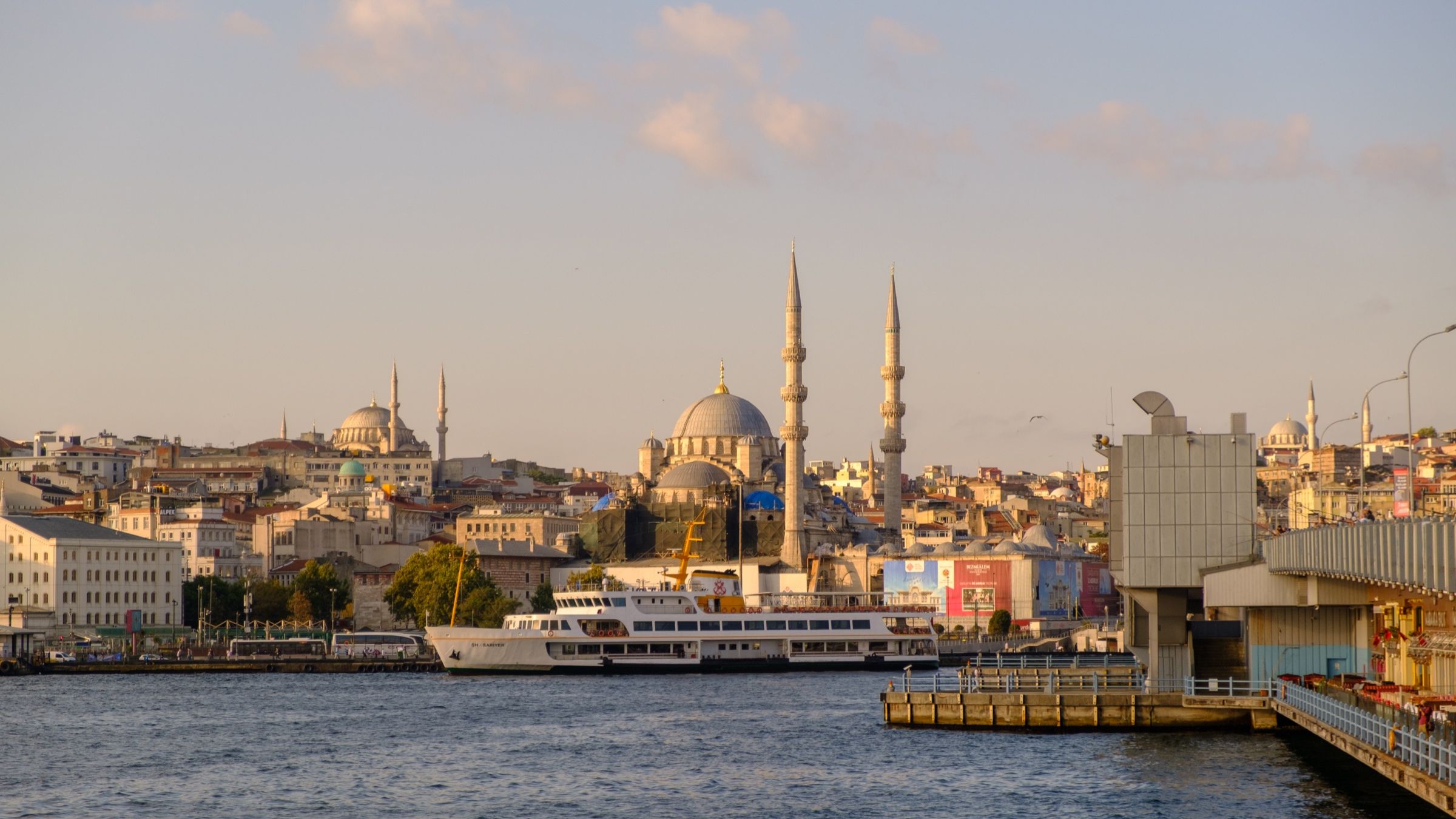 A Bosphorus ferry docked at Eminönü with Istanbul's mosque-topped skyline behind it at golden hour