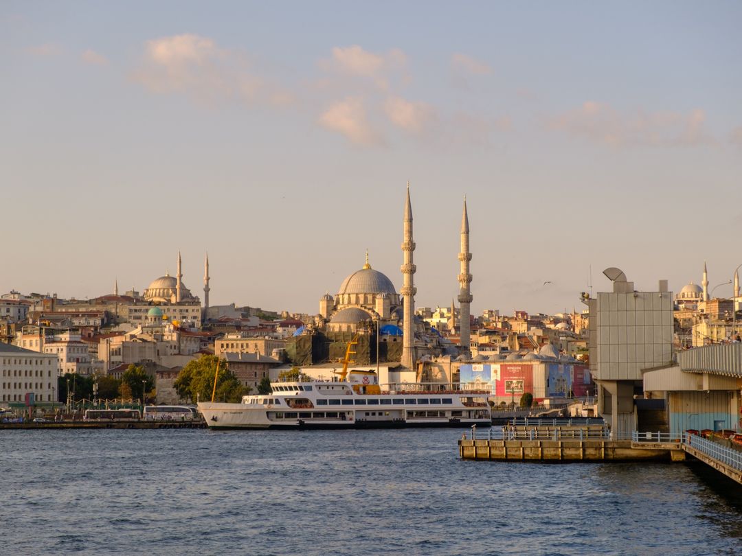 A Bosphorus ferry docked at Eminönü with Istanbul's mosque-topped skyline behind it at golden hour