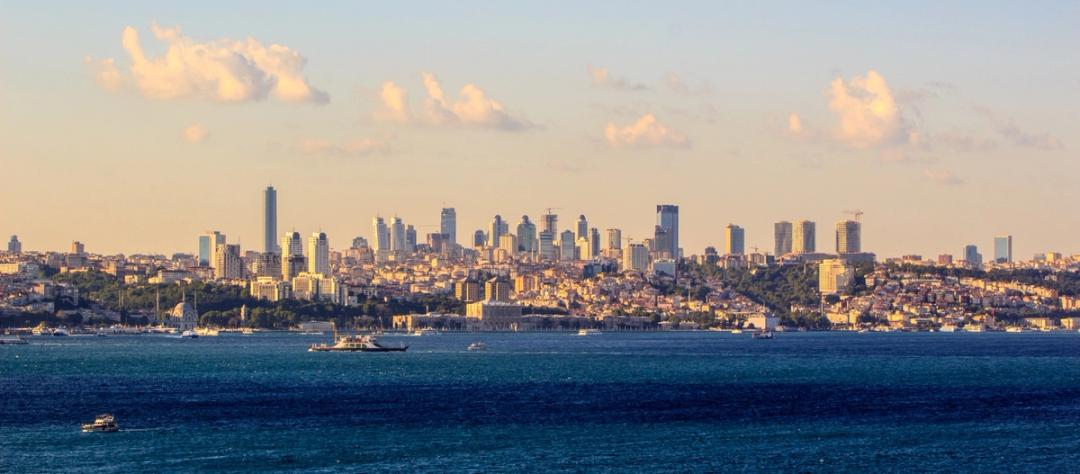 The Bosphorus strait with boats crossing in front of Istanbul's modern skyline at sunset