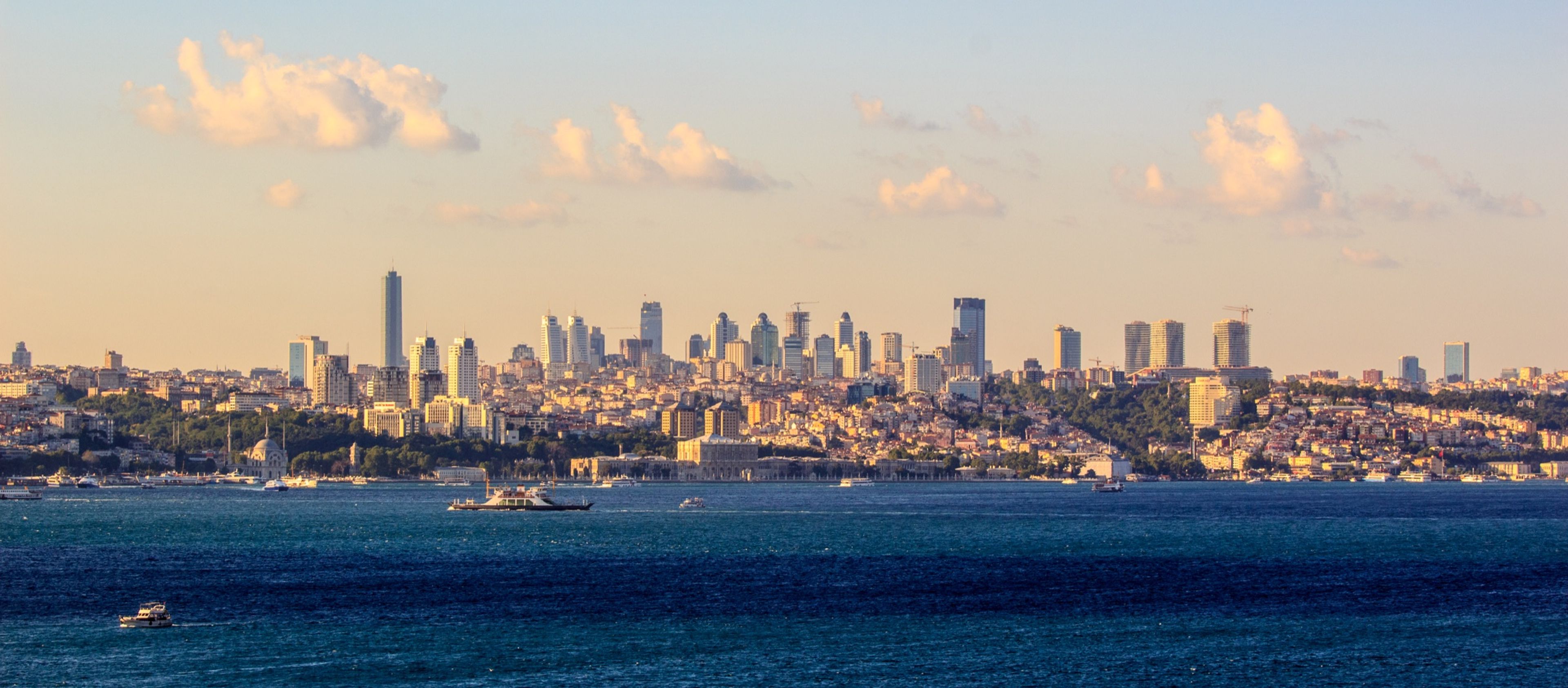 The Bosphorus strait with boats crossing in front of Istanbul's modern skyline at sunset
