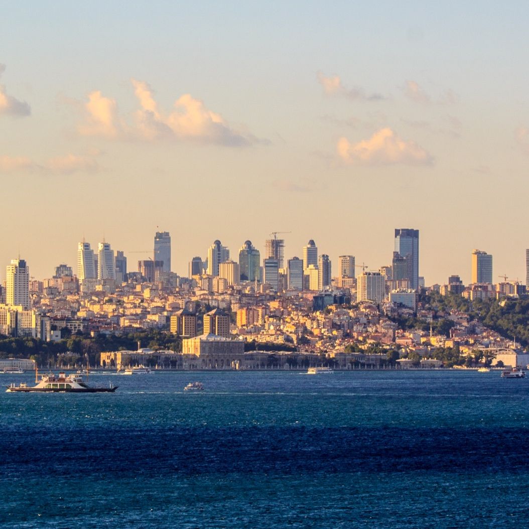 The Bosphorus strait with boats crossing in front of Istanbul's modern skyline at sunset