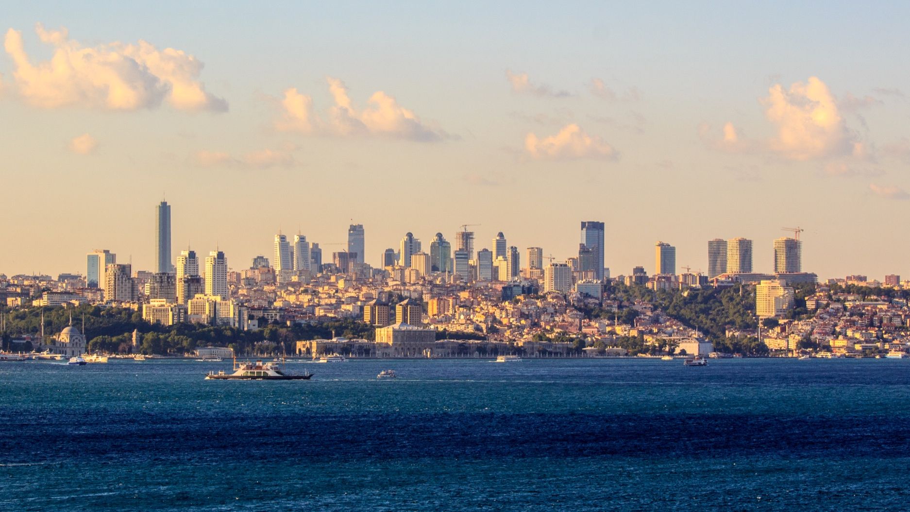 The Bosphorus strait with boats crossing in front of Istanbul's modern skyline at sunset