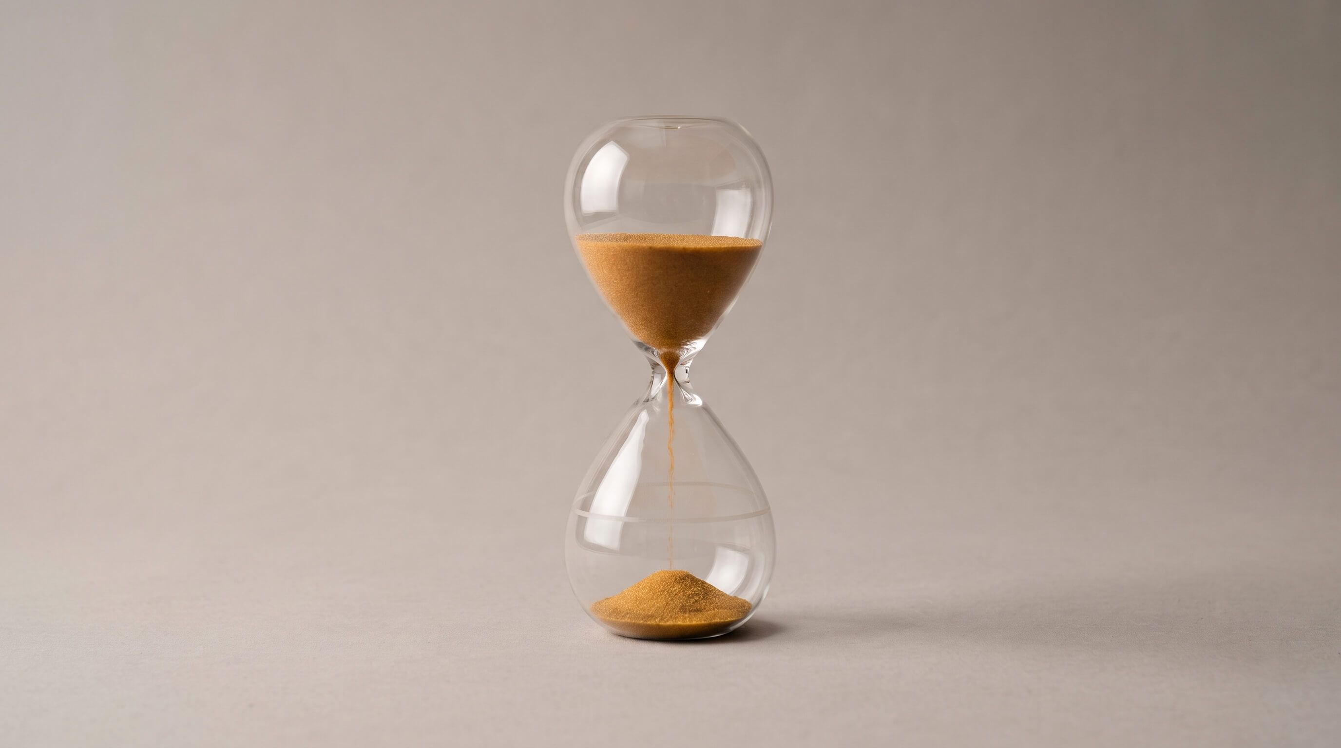 Hourglass with a small portion of sand and a faint outline in the lower chamber, showing the level it will reach.