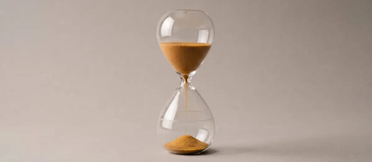 Hourglass with a small portion of sand and a faint outline in the lower chamber, showing the level it will reach.
