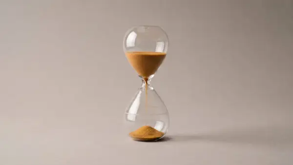Hourglass with a small portion of sand and a faint outline in the lower chamber, showing the level it will reach.