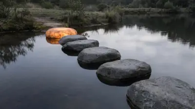 A row of stepping stones across still water, with only the last stone glowing.