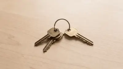 Four brass keys on a wooden table, one set slightly apart from the other three.