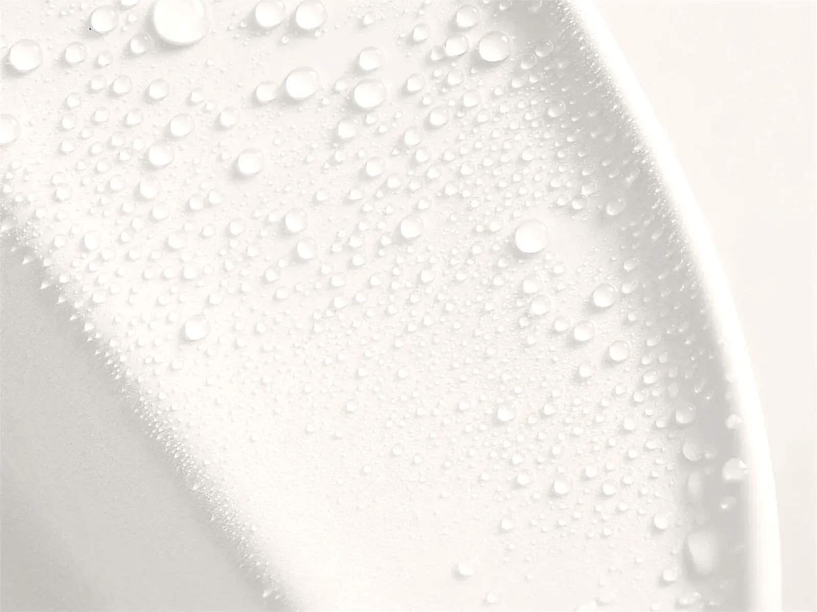 Gotas de agua sobre la superficie blanca de una bacha de porcelana, cerca del borde