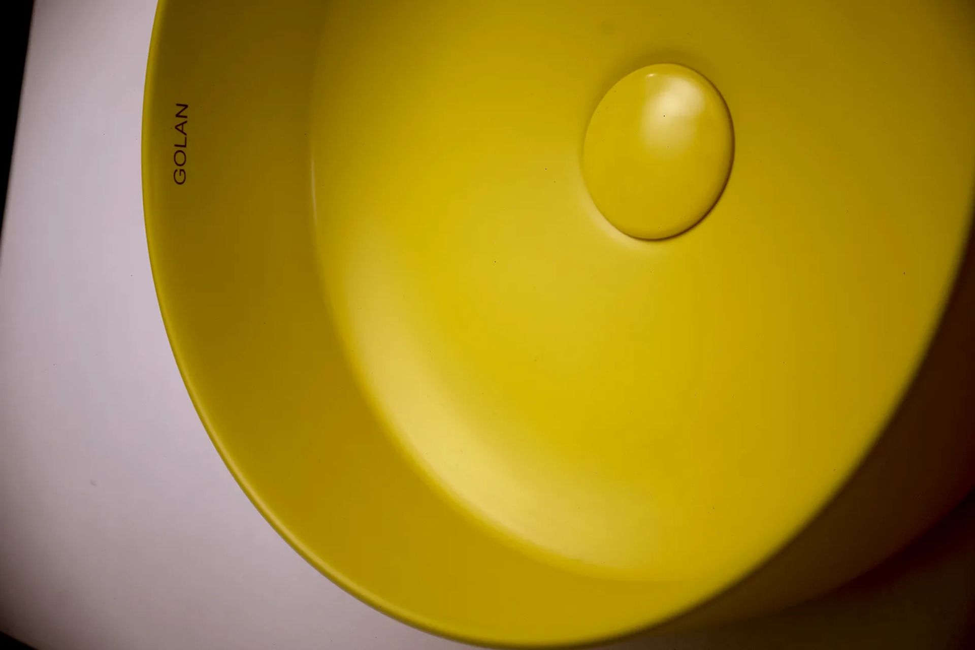 Interior de la bacha amarilla con el logotipo GOLAN en el borde y la tapa del desagüe