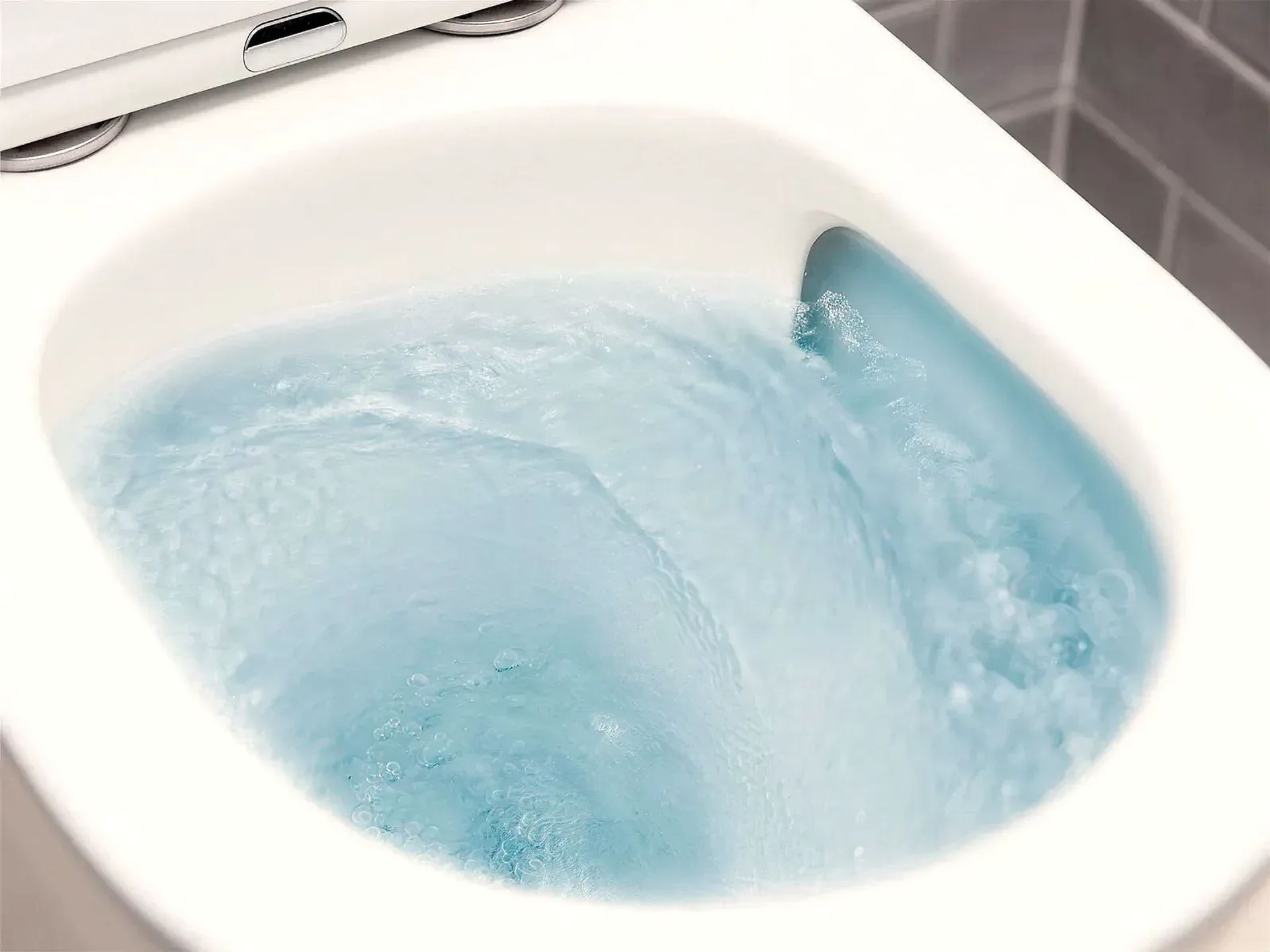 Interior de un inodoro sin aro con el agua de la descarga girando en espiral por todo el cuenco