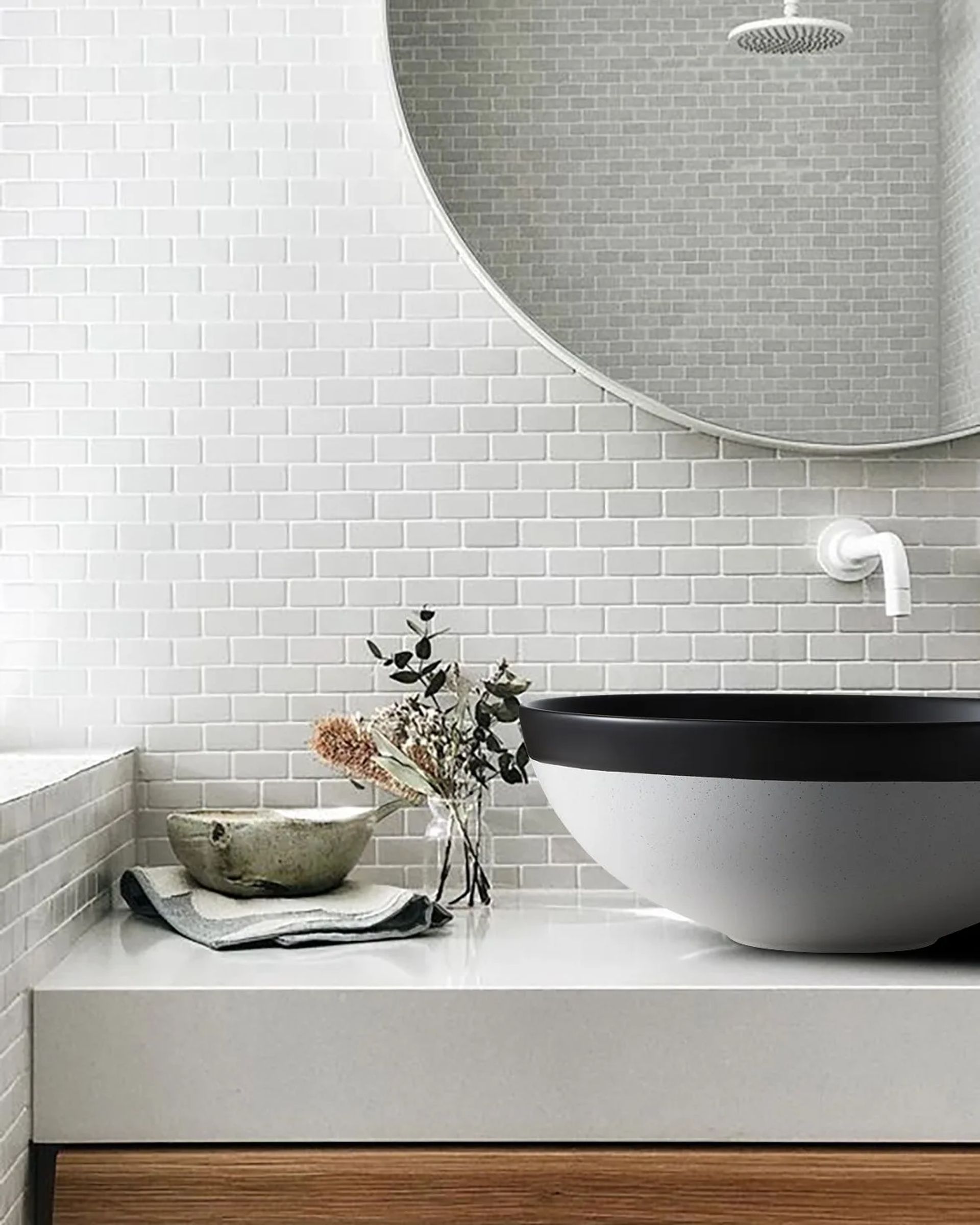 Bacha Osaka gris con borde negro sobre una mesada blanca, con espejo redondo y pared de azulejos