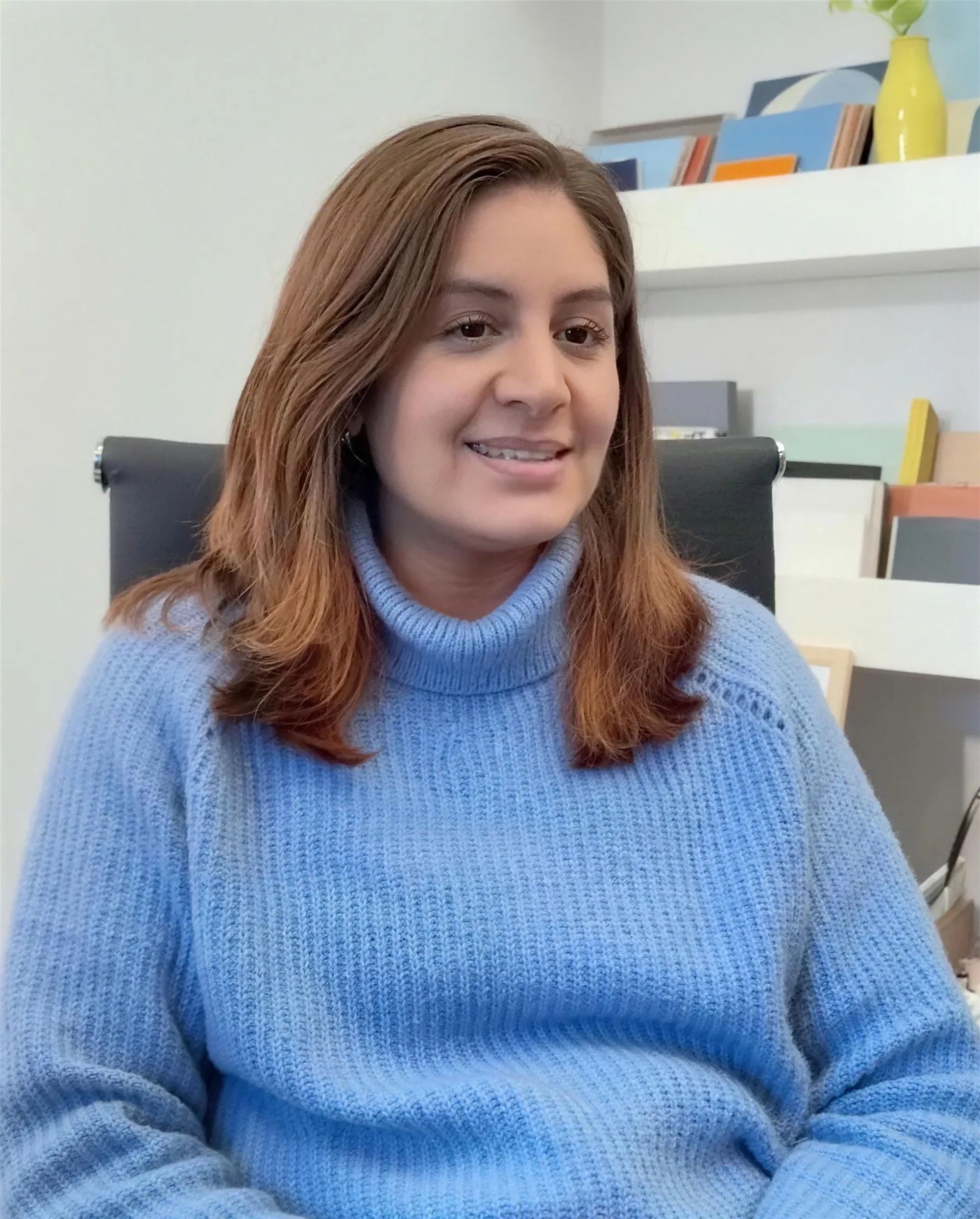 Mel Ruiz, de Libria Interiores, sentada en el estudio frente a la biblioteca de materiales