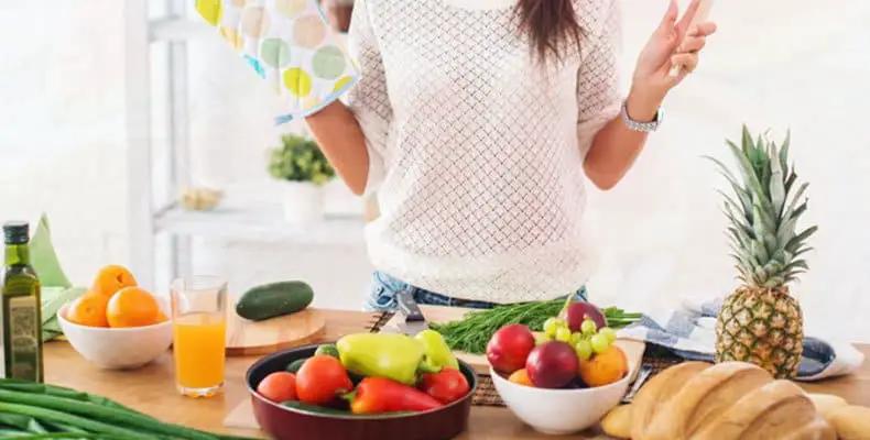 Mesa de cocina con frutas, verduras y otros alimentos.