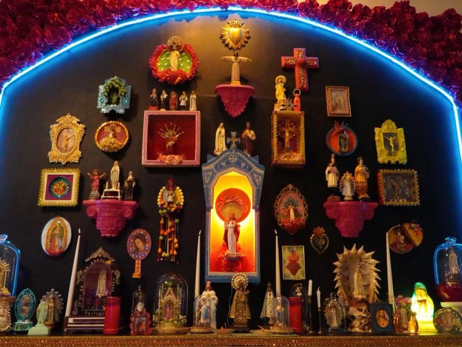 Altar principal con vírgenes, neón azul y rosas rojas
