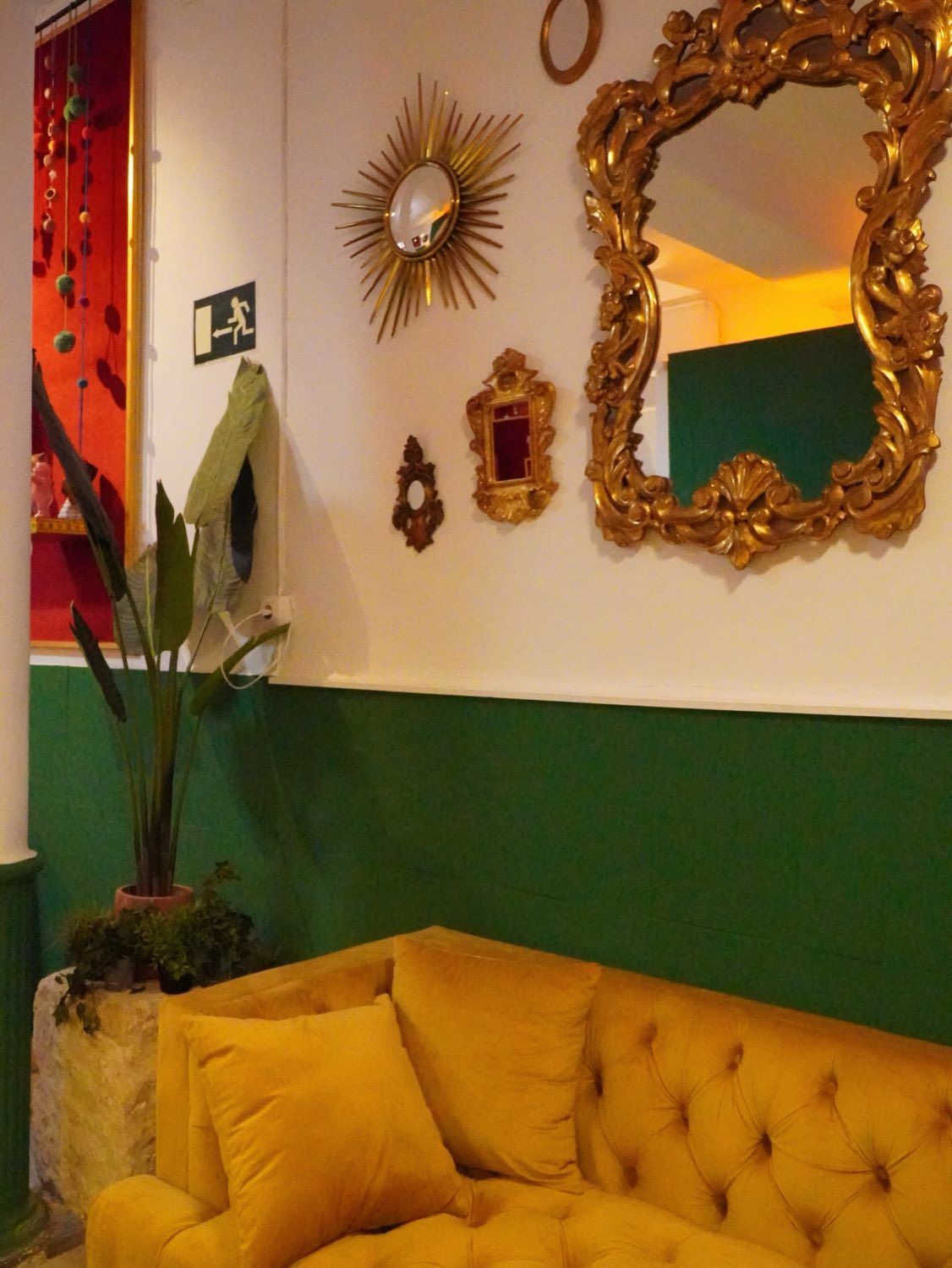 Sofá amarillo de terciopelo bajo espejos dorados