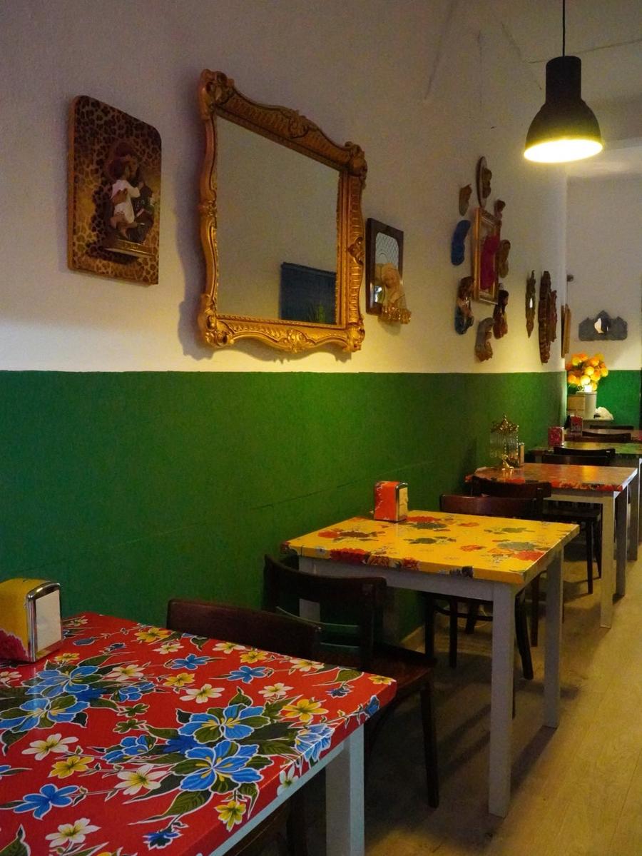 Mesas con manteles floreados y pared verde con espejos dorados