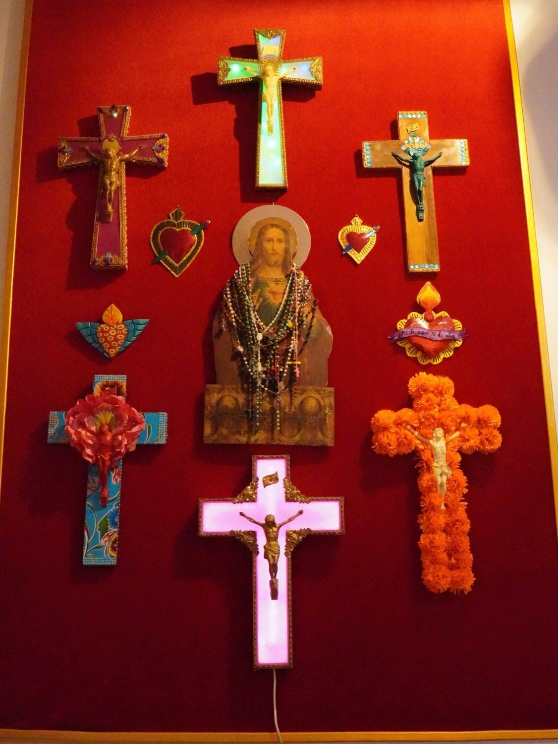 Pared roja con cruces de colores y Sagrado Corazón